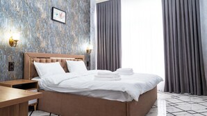 A hotel room with a large bed, two bedside lamps, a nightstand, and a picture on the wall. - GOLD STAR PALACE HOTEL (Samarkand)