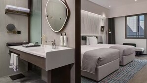 Quarto de hotel moderno com um espelho grande, toucador com amenities de higiene pessoal, cama com duas almofadas e janela com vista.