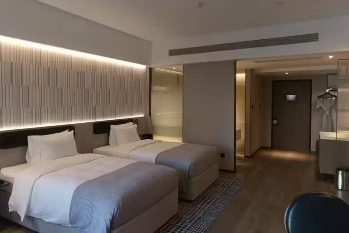 A modern hotel room with two beds, a desk, and a TV.