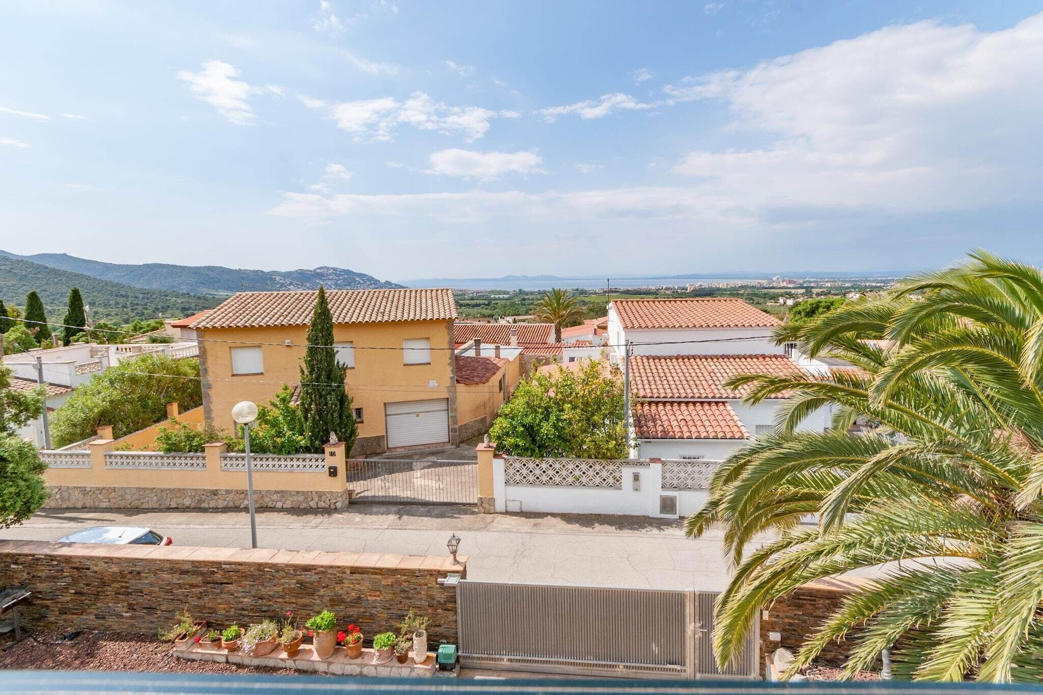 Un quartiere residenziale con case, un muro di pietra e una palma.
