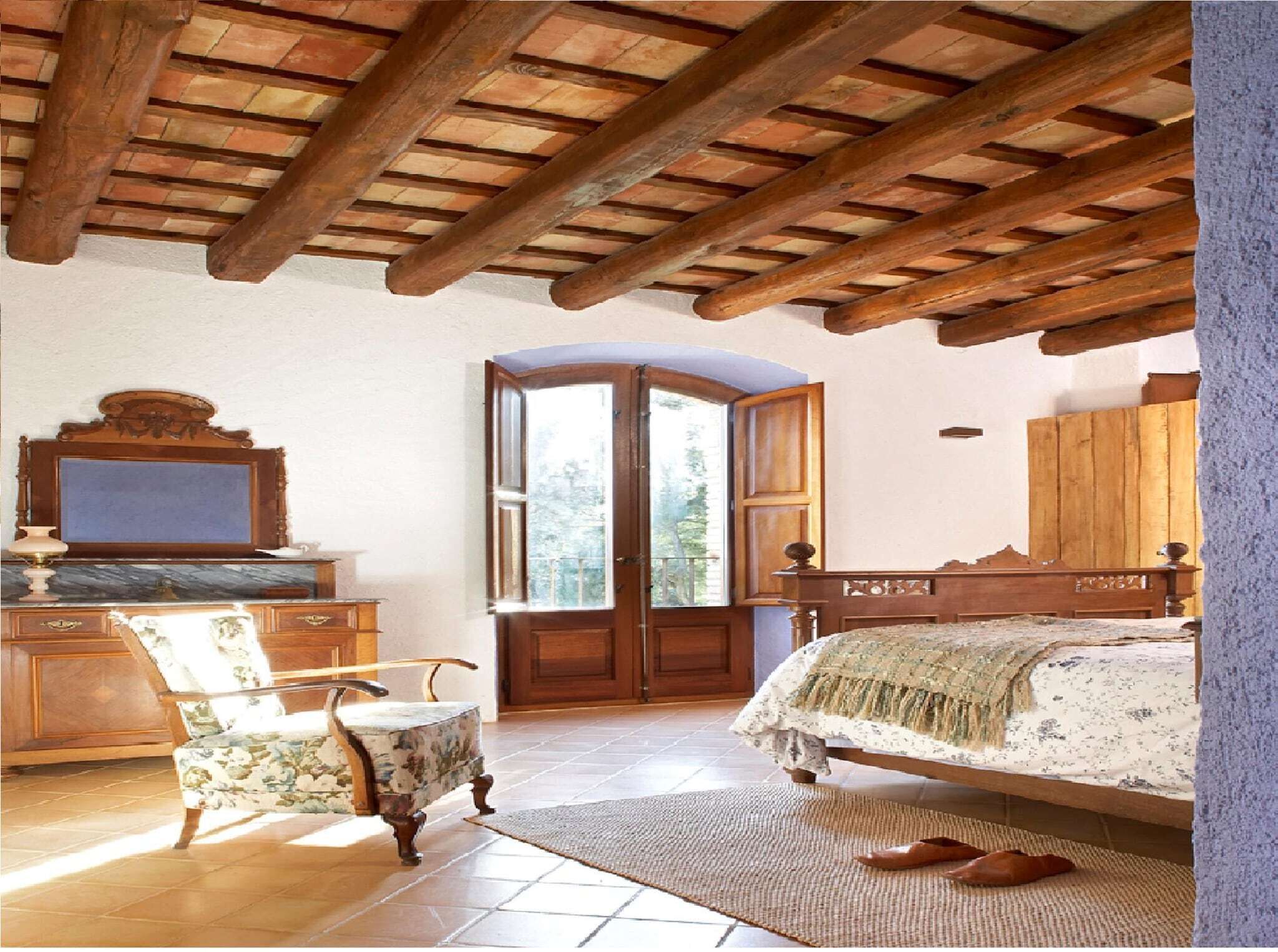 A bedroom with a wooden ceiling, a bed, a chair, a dresser, and a mirror.