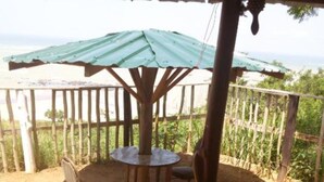 Un espace extérieur aménagé, abrité et doté d’une table et de chaises, entouré d’une clôture en bois et offrant une vue sur la verdure.