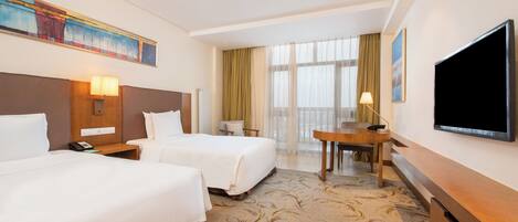 A hotel room with two beds, a desk, a television, and a painting on the wall.