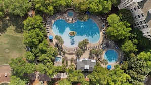An aerial view of a resort with multiple swimming pools surrounded by lush greenery and palm trees.