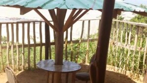A covered outdoor seating area with a table and chairs, surrounded by a wooden fence and a view of greenery. - Special Place For Special People - Room 2 (Abuesi)