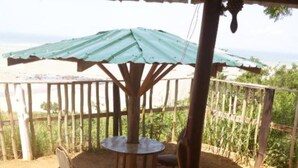 A covered outdoor seating area with a table and chairs, surrounded by a wooden fence and a view of greenery. - Special Place For Special People - room 4 (Abuesi)
