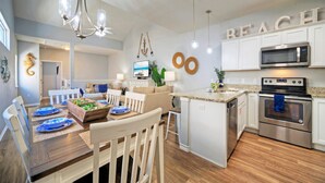 A modern kitchen with white cabinets, a built-in microwave, and a stainless steel oven.