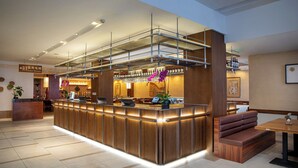 Un hall d’hôtel moderne comprenant un comptoir d’accueil, un ascenseur pour les clients et un espace salon.