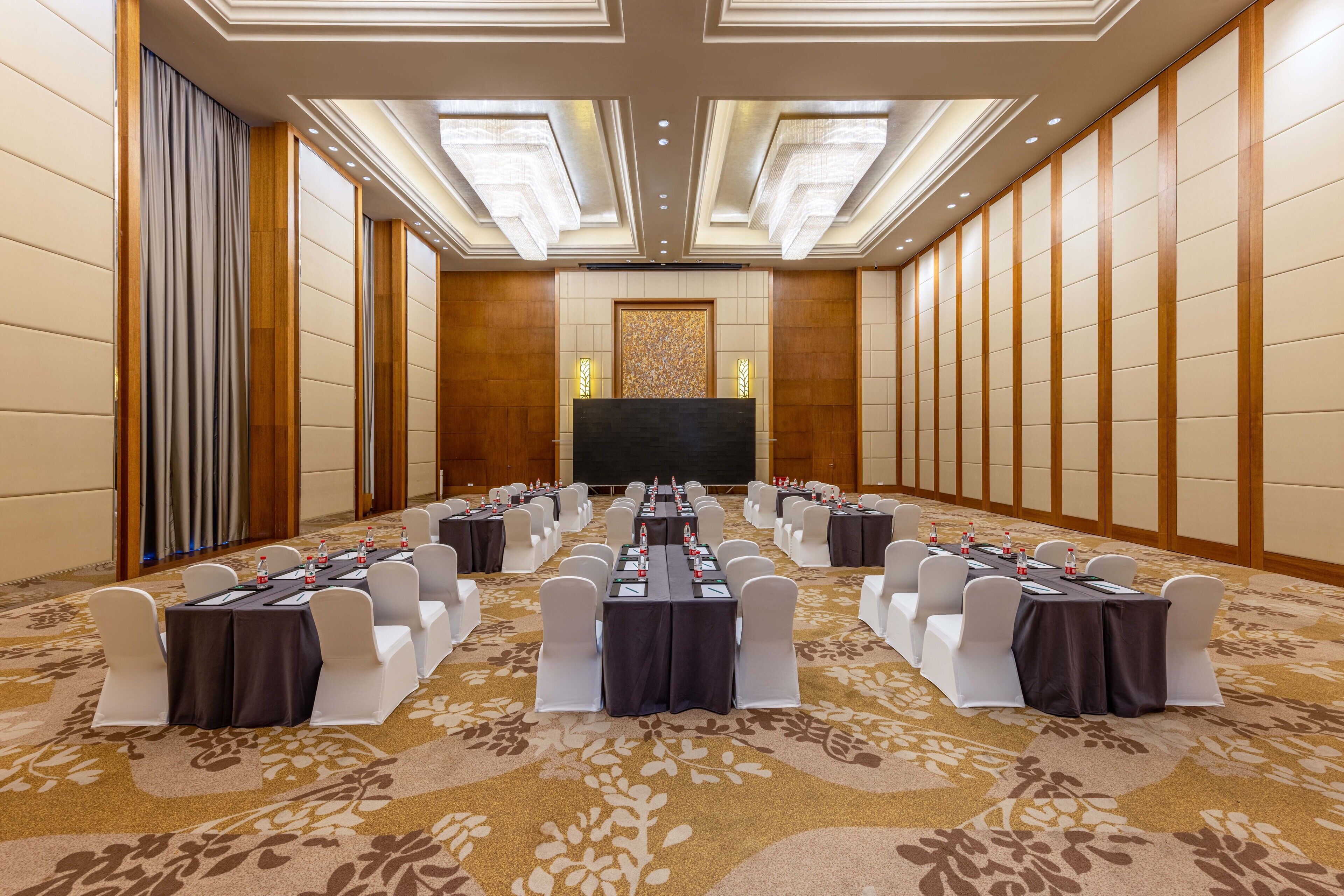 A conference room with a long table, white chairs, and a carpeted floor.