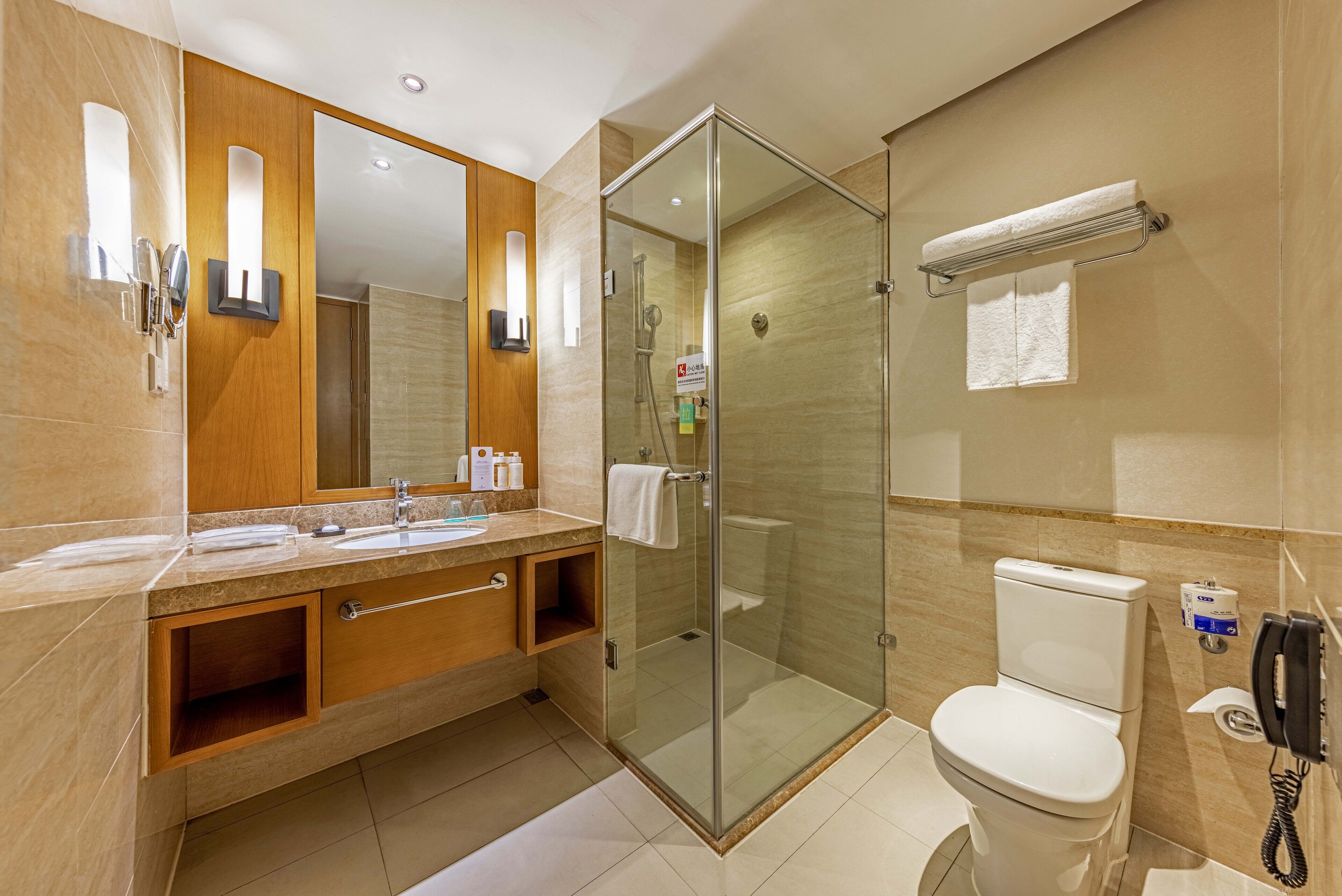 A modern bathroom with a glass-enclosed shower, a white toilet, a vanity with a mirror, and a towel rack.
