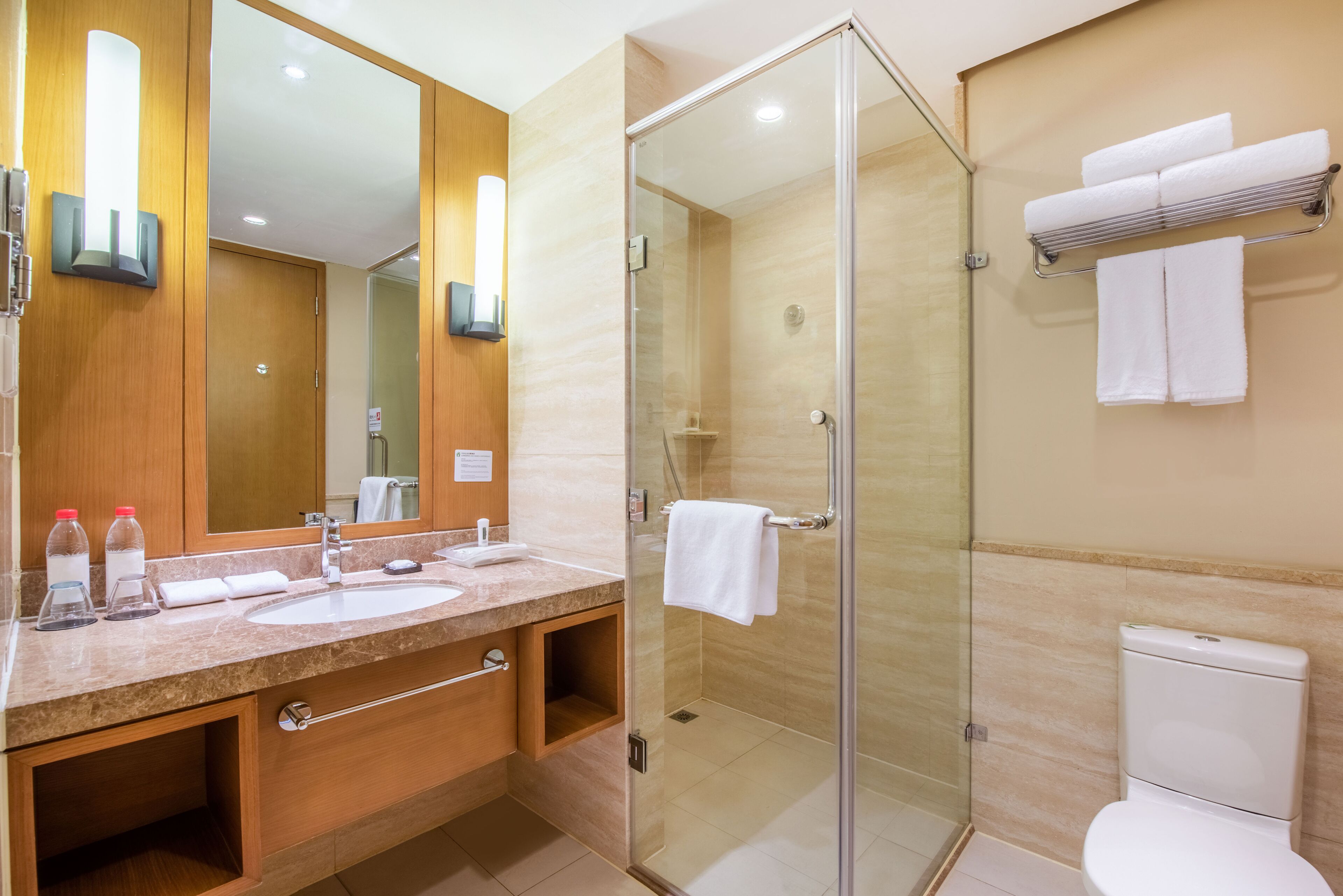 A modern bathroom with two sinks, a glass-enclosed shower, and a toilet.