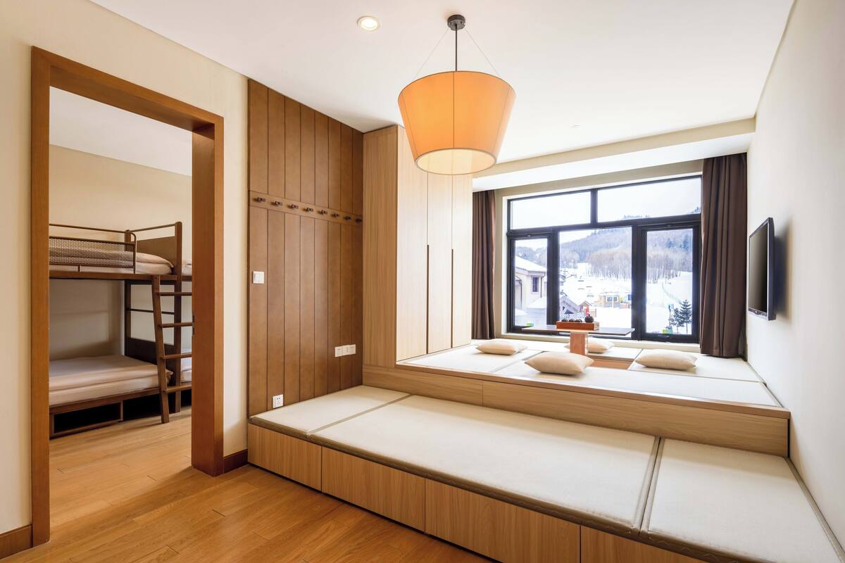 Une chambre moderne avec un lit superposé, un coin salon intégré et une grande fenêtre offrant une belle vue.