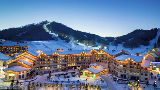 Un grand hôtel à plusieurs étages, avec une piste de ski en arrière-plan.