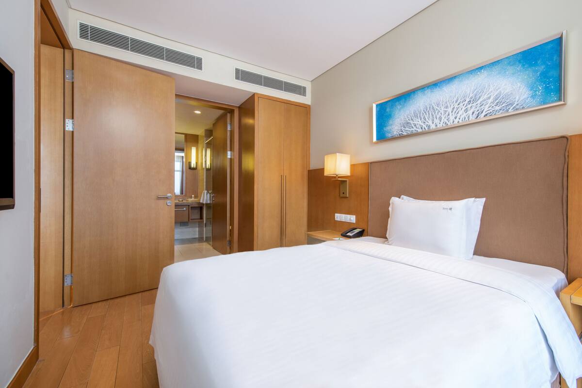 Une chambre d’hôtel avec un grand lit, une armoire en bois et un tableau au mur.