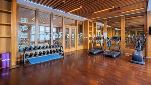 Une salle de sport moderne dotée d’un plancher en bois, d’appareils d’exercice et de murs recouverts de miroirs.