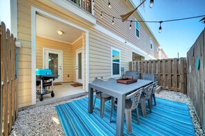 Un jardin avec une table et des chaises de patio, un barbecue et une clôture en bois.