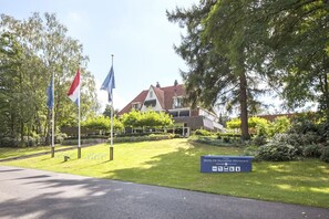 Hotel De Salande Heuvelrug features a traditional gabled roof and a well-manicured lawn.