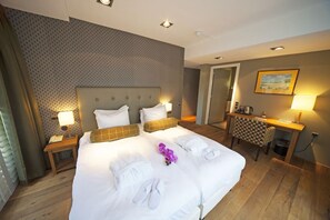 Comfortable retreat with a large bed, two bedside tables, and a desk with a chair, set against a patterned backdrop.