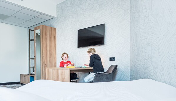 Relax in a spacious room with a large bed, flat-screen TV, and a desk for work or relaxation.