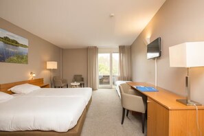 Relax in this stylish room with two single beds, a flat-screen TV, and a comfortable chair.