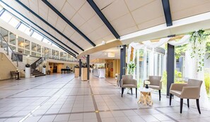 Experience the grandeur of our hotel lobby, featuring a soaring ceiling, elegant staircase, and comfortable seating areas.