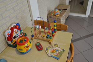 Cozy room designed for families, featuring a table with toys and a comfortable chair.