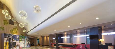 A spacious lobby with a checkered floor, a reception desk, and decorative spherical light fixtures.