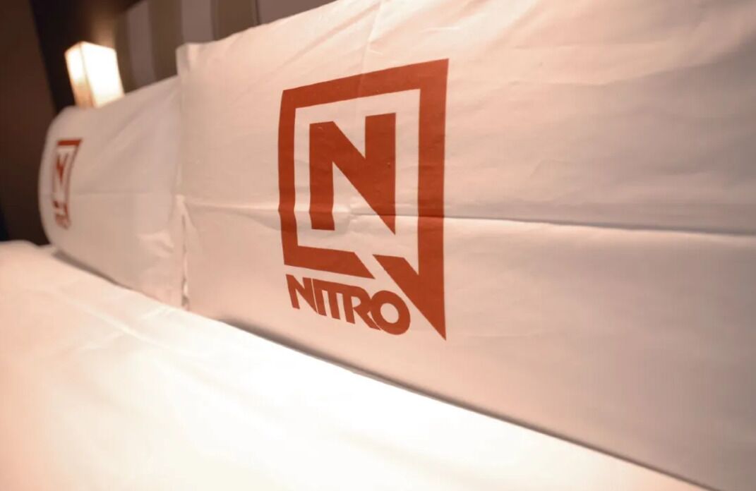 A hotel bed with a logo on the pillowcase.