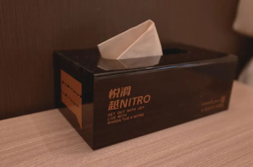 Una caja de pañuelos con texto y un pañuelo sobre una superficie de madera.