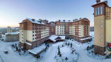 Et stort, flerlags hotel med en central gårdsplads omgivet af sneklædte træer.