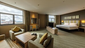 A hotel room with a bed, a desk, a TV, a sofa, and a view of the mountains. - Wanda Yue Changbaishan (Baishan)