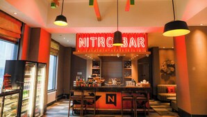 A bar area with a neon sign reading "NITROBAR," bar stools, and a counter with various bottles and glasses. - Wanda Yue Changbaishan (Baishan)