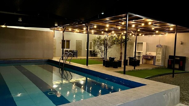 An outdoor swimming pool with a covered seating area and a small garden. - Apple Mango Resort (Silang)