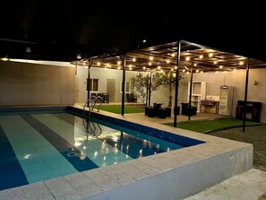 An outdoor swimming pool with a covered seating area and a small garden. - Apple Mango Resort (Silang)