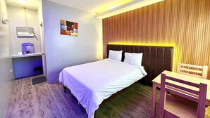 A hotel room with a bed, a desk, and a chair. - Apple Mango Resort (Silang)