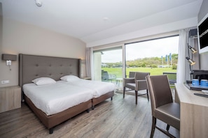 Relax in a spacious room with a large bed, desk area, and sliding glass door leading to an outdoor seating area with a view.