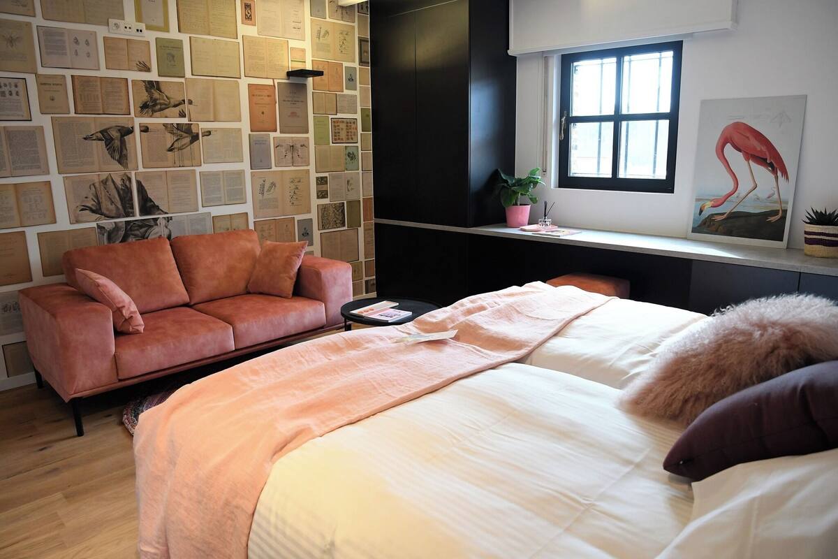 Un dormitorio ordenado con cama, sofá, una mesita y ventana con vistas.