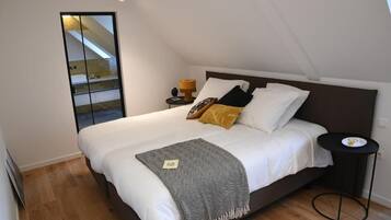 Une chambre avec un grand lit, une table de chevet, une lampe et une vue sur un balcon.