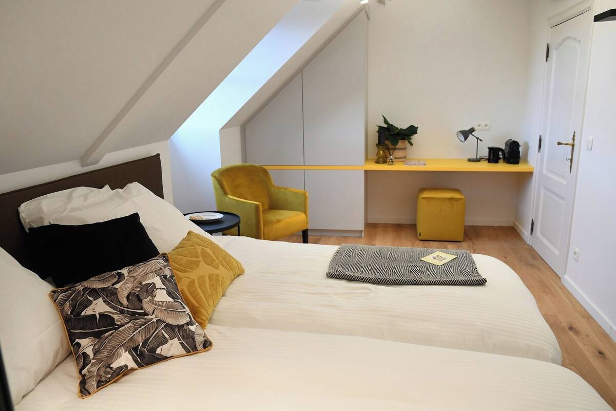 Un dormitorio con dos camas, un escritorio, una silla y un mueble bajo.