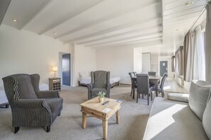 Relax in this spacious living room with a sofa, dining table, and coffee table, perfect for unwinding and dining.