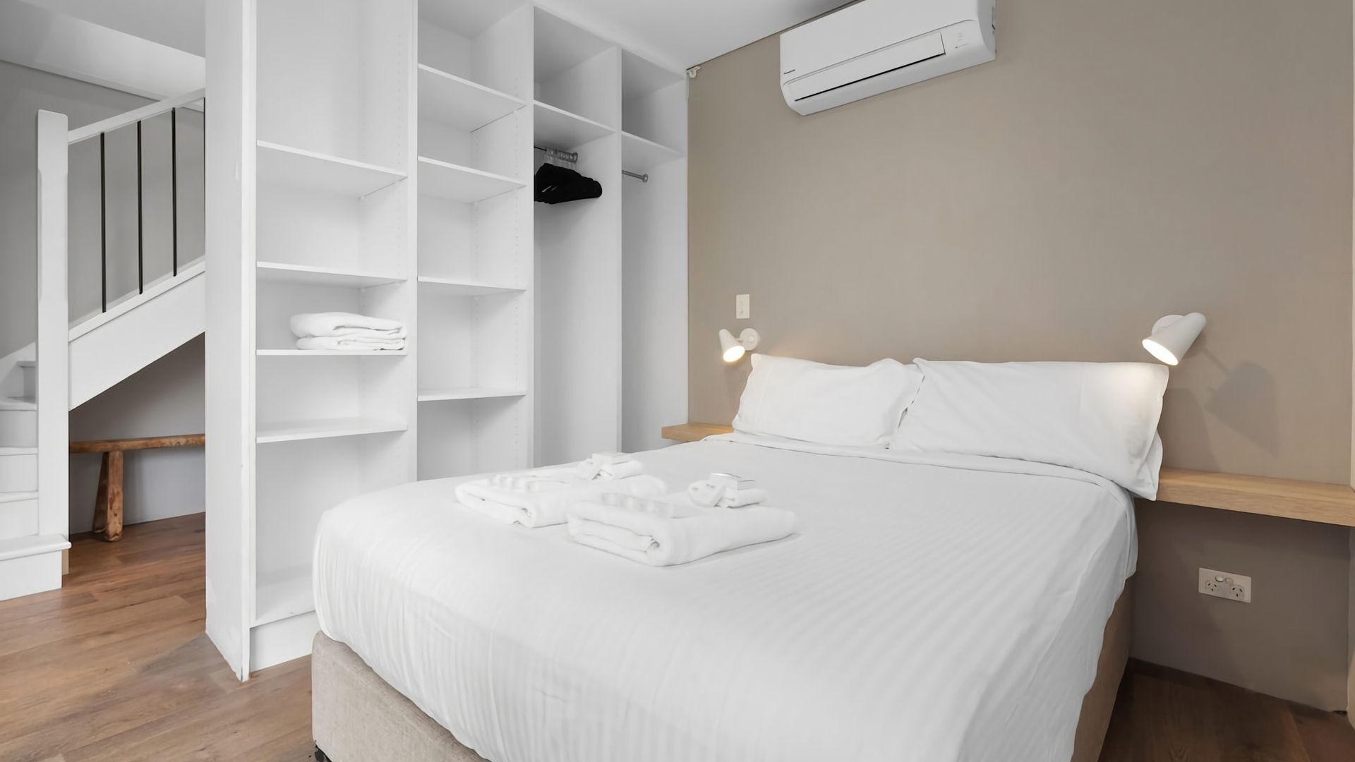 Habitación de hotel con cama, armario empotrado, mesita de noche y aire acondicionado de pared.