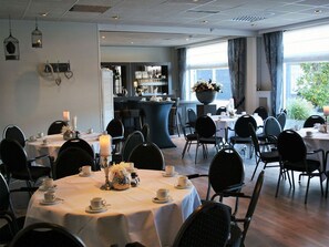 Formal dining area with round tables, black chairs, and elegant centerpieces.