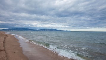 Een strand met een zandstrand en een rustige zee onder een bewolkte lucht.
