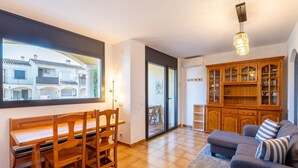 Un salón amplio con una mesa de comedor de madera y sillas, un sofá gris y un aparador de madera con puertas de cristal.