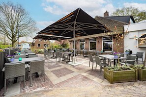 Guests can dine al fresco at this charming outdoor seating area, surrounded by lush greenery and shaded by a large umbrella.
