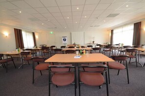 Host meetings and presentations in this well-equipped conference room with tables, chairs, and a projector screen.