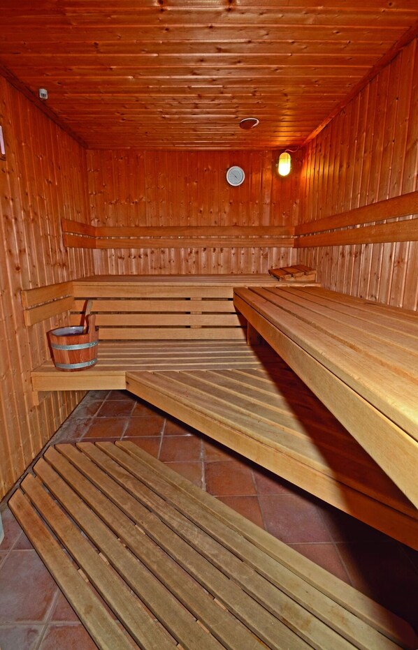 Relax in a serene sauna with a wooden bench and tiled floor.