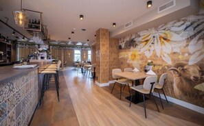 Enjoy a meal at the restaurant with a long counter and comfortable bar stools, surrounded by a mix of high and low tables and a beautiful mural.