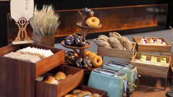 A variety of baked goods displayed on wooden stands and trays, including donuts, pastries, and bread.
