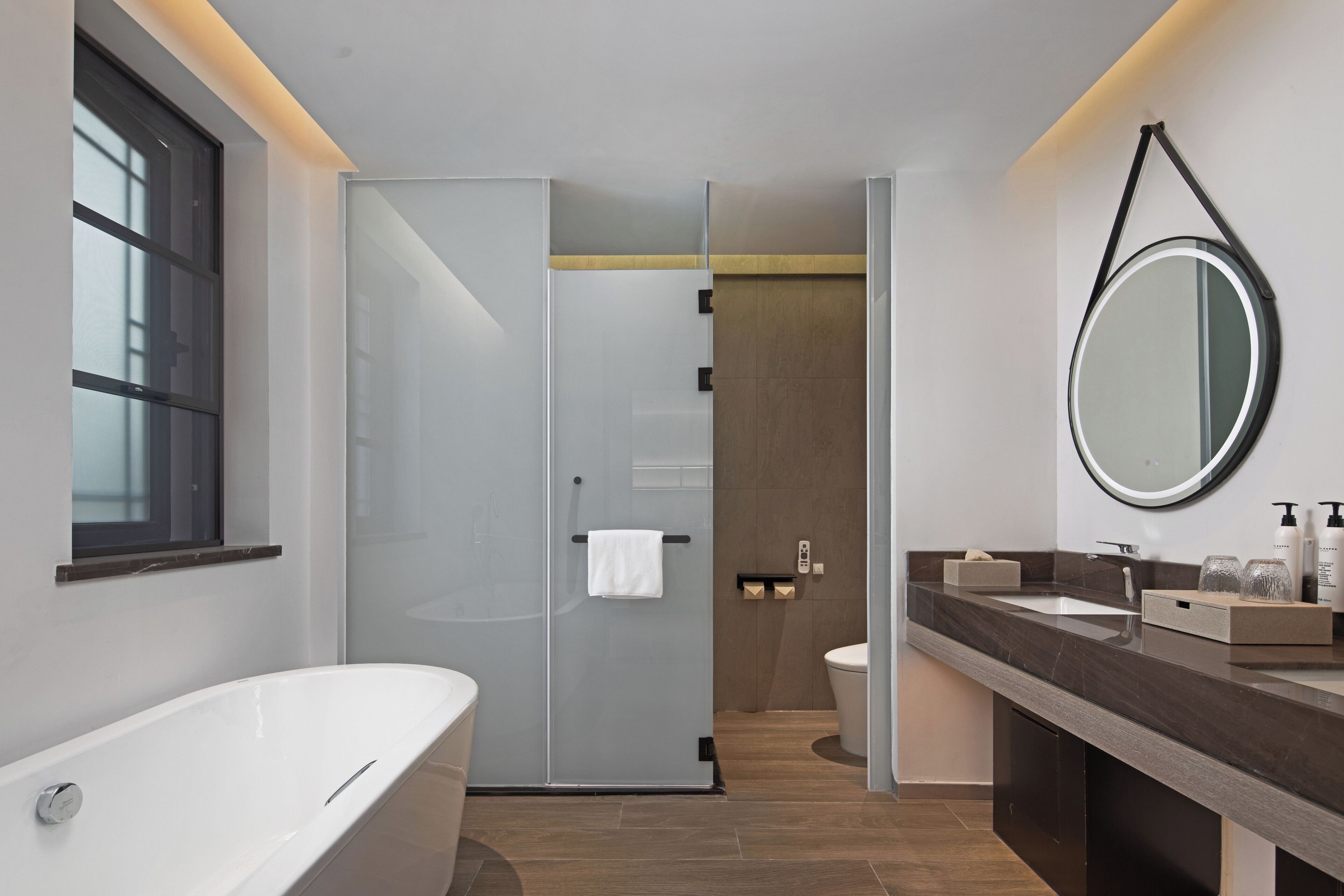 Un baño moderno con una bañera independiente, cabina de ducha con mampara de vidrio y tocador con espejo.